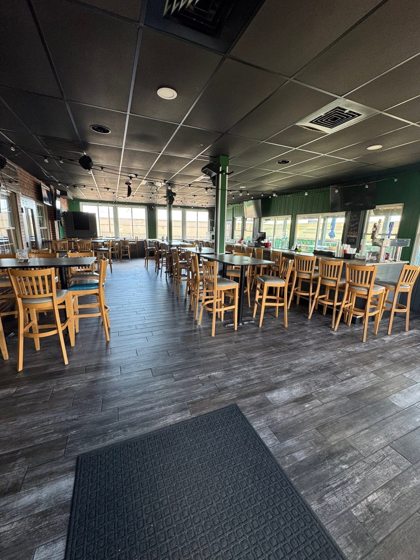 Tables, bar stools, televisions, and the bright dining room at Mayfair Bar and Grill